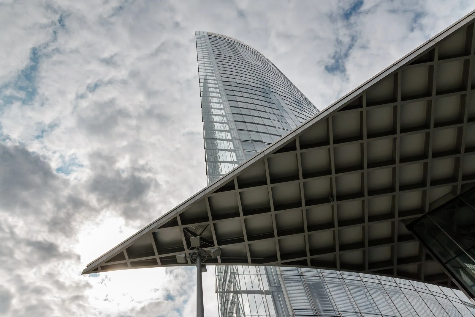 A modern glass skyscraper rising against a dramatic sky