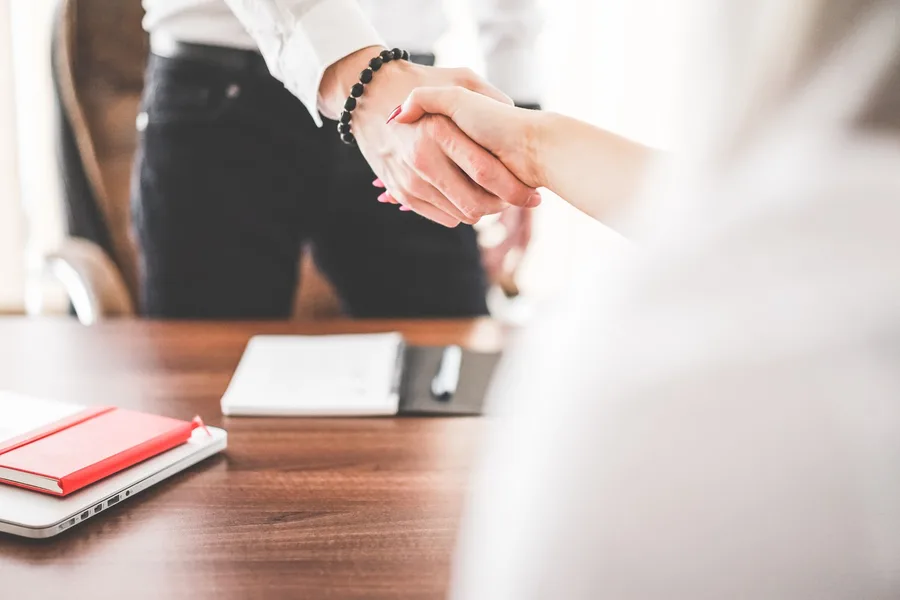 A business handshake across a desk, signalling partnership